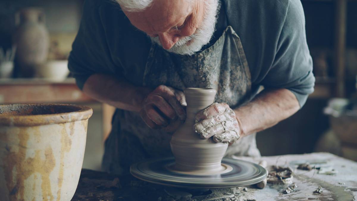 what is wheel throwing in pottery: beginner hands centering wet clay on a spinning pottery wheel