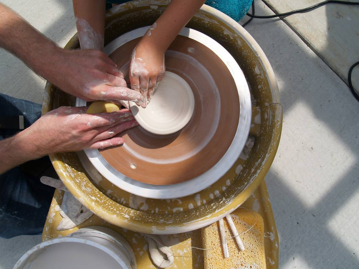 pottery techniques wheel throwing: student practicing centering clay on electric pottery wheel in home studio