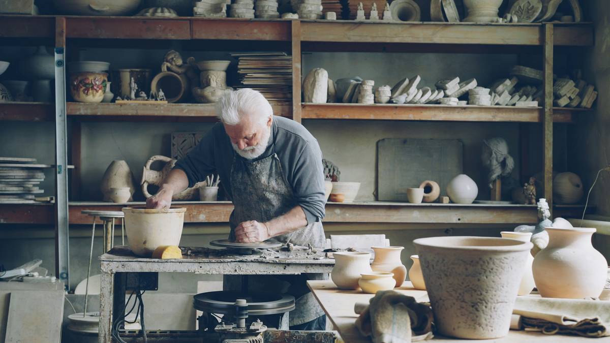 Beginner practicing throwing on a pottery wheel with hands shaping wet clay